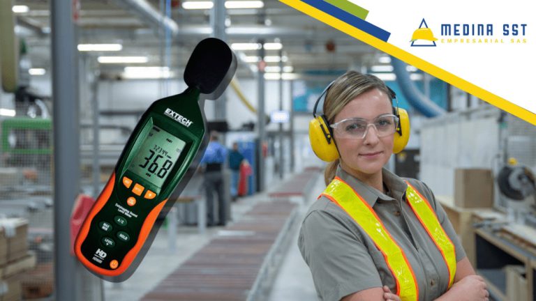 Una trabajadora equipada con casco y protectores auditivos realiza mediciones de ruido con un sonómetro dentro de una instalación industrial, destacando la aplicación de medidas de seguridad para proteger la audición en ambientes de alto ruido.