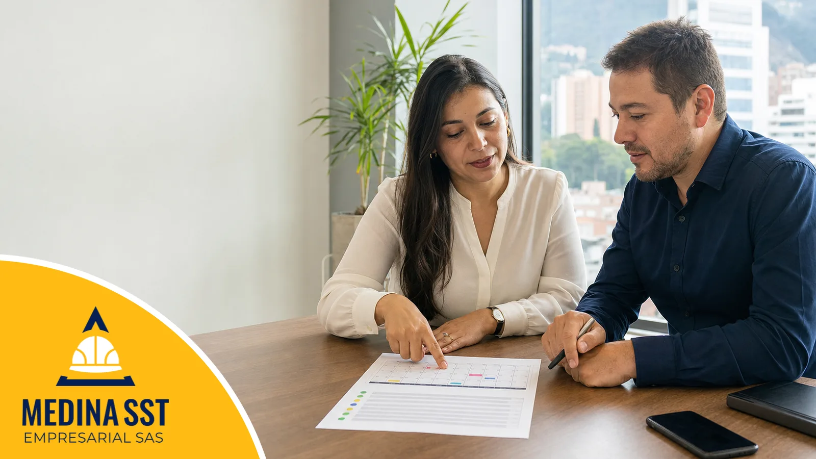 Responsable del SG-SST y gerente de una empresa colombiana revisando juntos el plan de trabajo anual sobre un calendario con metas y fechas