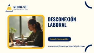 Trabajadora colombiana en su puesto al final de la tarde, escribiendo en el portátil con el teléfono boca abajo sobre el escritorio